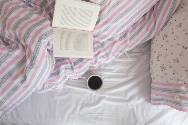 istock Cup of hot coffee and book on the bed 1135257207