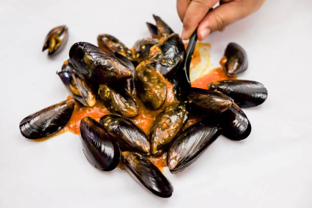 Close up of males hand holding sauteed mussels