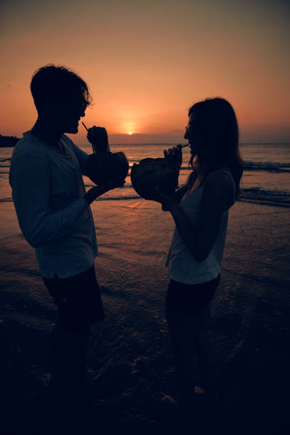 istock Couple drinking cocnut juice while watching the sunset over the ocean in Bali, Indonesia. 1135266441