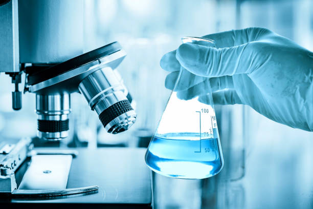 istock microscope with hand of scientist holding flask with lab glassware in laboratory background, science laboratory research and development concept 1135269815