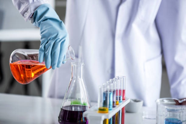 istock Scientist holding sampling oil or chemical liquid in flask with lab glassware in laboratory background. 1135270292