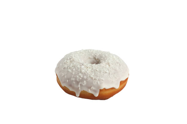 Appetizing donut in white glaze with the decoration of coconut chips on a white background. Isolated. stock photo