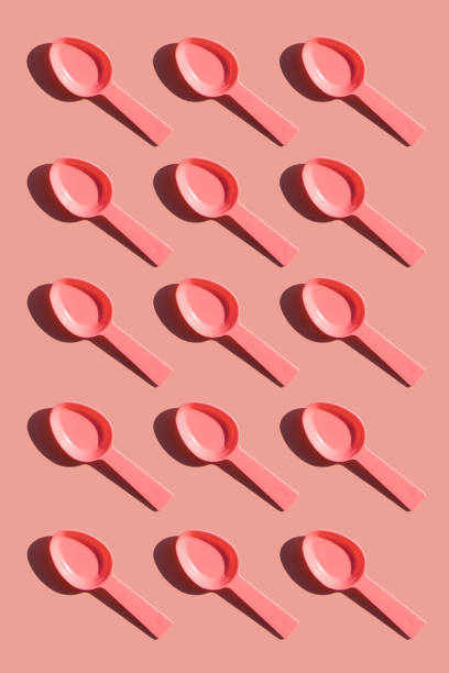 istock Plastic pink spoons in a row on pink background. 1135274330