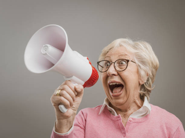 Cheerful senior lady shouting into a megaphone