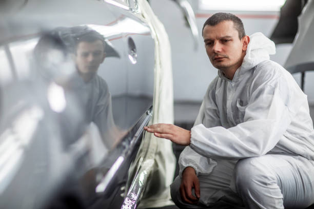 istock Car painting technician checking out paint consistency on a freshly painted door segment 1135274497