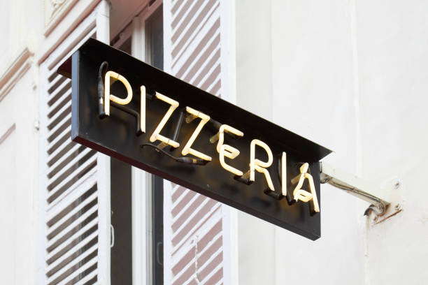 istock Pizzeria restaurant black sign with white illuminated text in Italy 1135275478