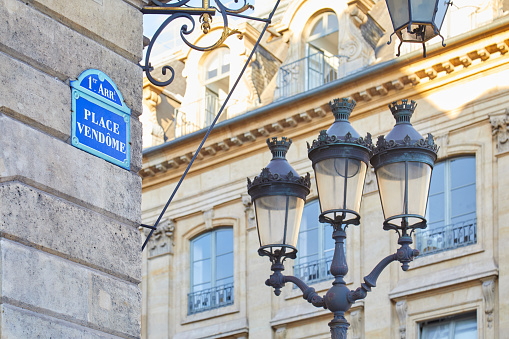 Famous Place Vendome corner with street sign and lamp in Paris, France.