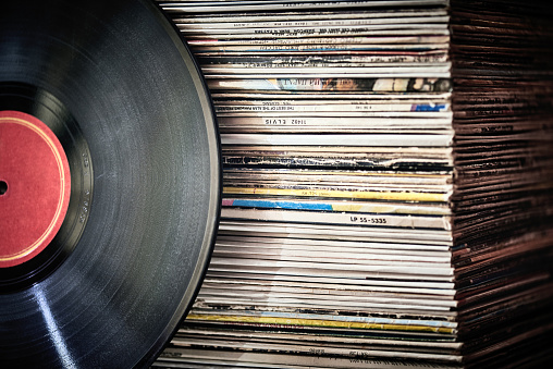 Vinyl record in front of a collection of albums, vintage process. Copy space for text