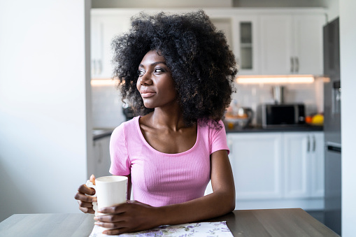 African woman sitting at home and drinking coffee.