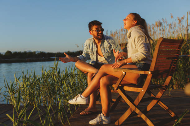 istock Young couple sitting by the river and laughing during the sunset 1135289370