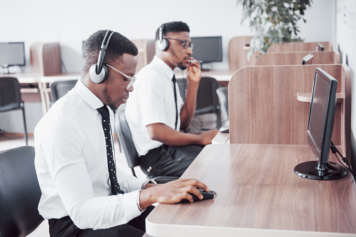 African american customer support operator with hands-free headset working in the office.