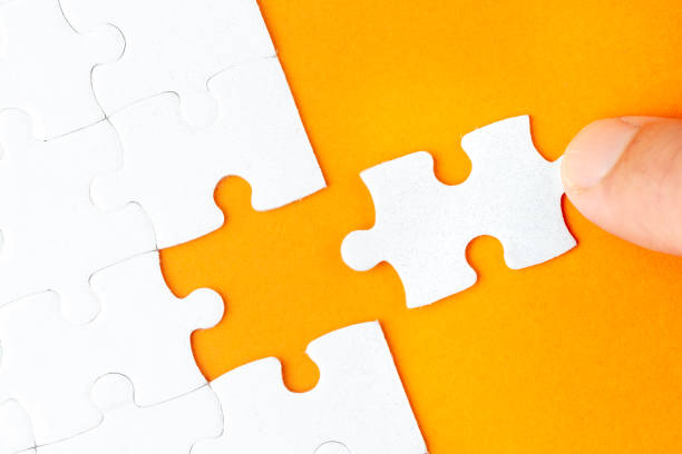 istock Hand holding piece of white puzzle on orange background 1135292433