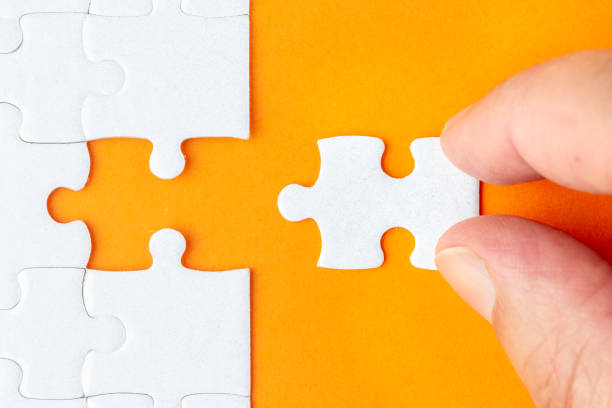 istock Hand holding piece of white puzzle on orange background 1135292446
