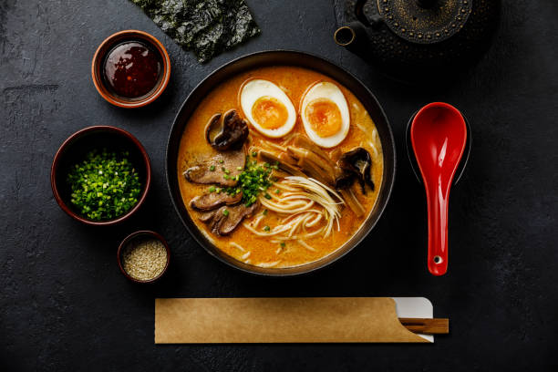 Ramen asian noodle in broth with Beef tongue meat, mushroom and Ajitama pickled egg in bowl on dark background stock photo