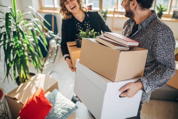 istock Young couple carrying cardboard boxes in new home 1135293040