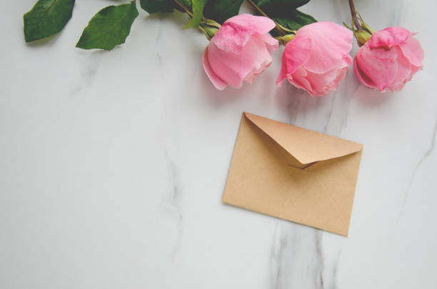 istock Pink roses and a craft envelope on marble table.Concept of greeting 1135293865