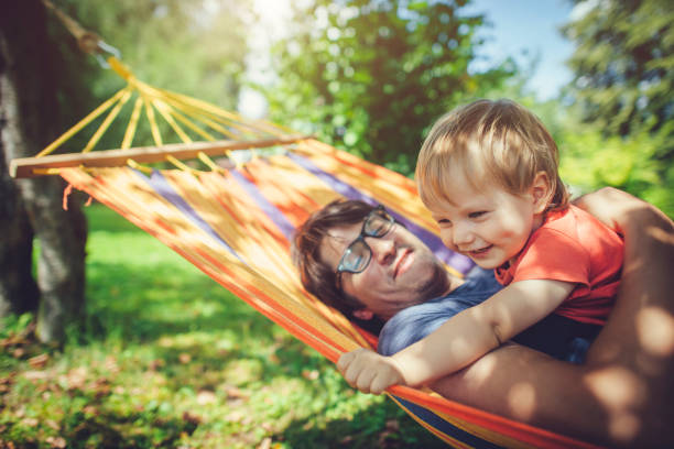 ハンモックで春夏の日を楽しむ家族 - swing child swinging front or back yard ストックフォトと画像