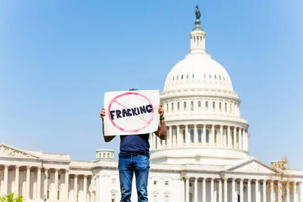 Man protest in front of the USA capitol in Washington holding sign saying no fracking for oil or gas