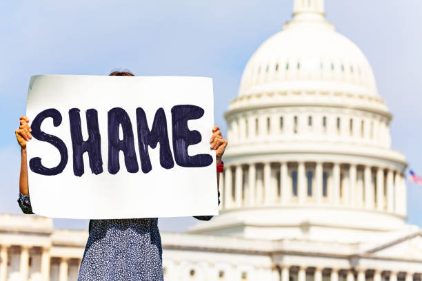 istock Protester holding sign shame in her hands hiding face 1135295602