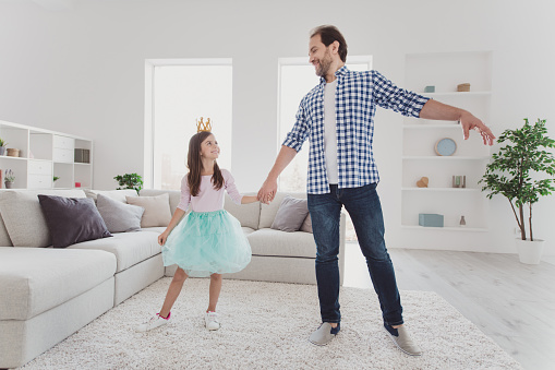 Full length body size portrait of nice lovely attractive cheerful cheery positive pre-teen girl handsome dad daddy holding hands dancing dream holiday in modern light white interior room indoors.