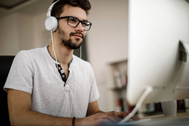 istock Teenage boy enjoying music and working on his computer 1135301298
