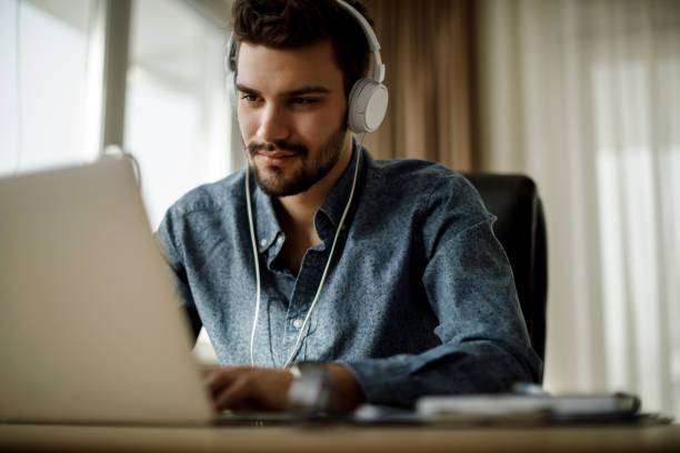 istock Young man using laptop and listening to music 1135301575