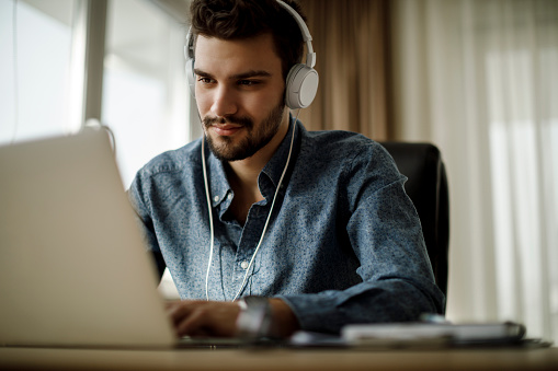 Young man using laptop and listening to music