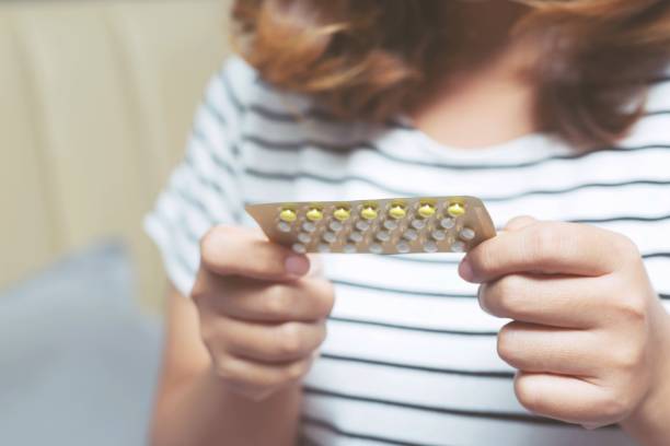 donna mani aprendo pillole anticoncezionale in mano sul letto in camera da letto. mangiare pillola contraccettiva. - estrogeno foto e immagini stock