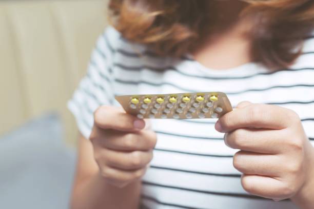 kobieta ręce otwarcie pigułki antykoncepcyjne w ręku na łóżku w sypialni. jedzenie pigułki antykoncepcyjnej. - contraceptive zdjęcia i obrazy z banku zdjęć