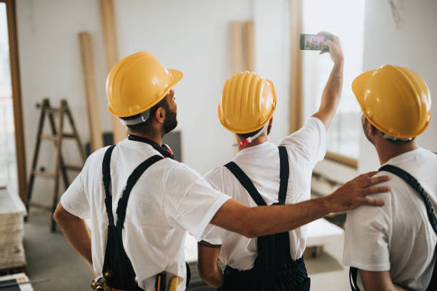 istock Rear view of construction workers taking selfie during home renovation process. 1135305978