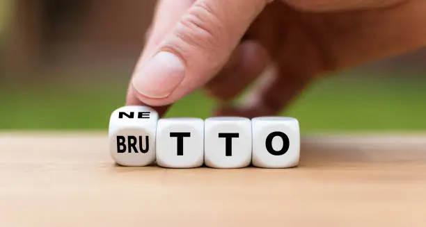 Hand turns a dice and changes the German word "BRUTTO" ("before taxes" in English) to "NETTO" ("after taxes" in English).