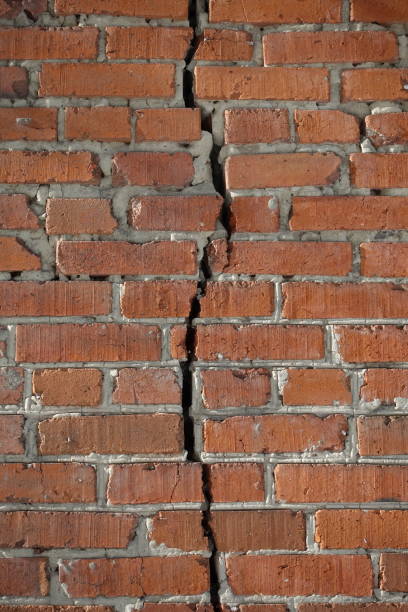 istock Red brick wall is divided by a vertical crack. Separation concept 1135314757