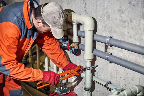 Plumber worker repairs the heating system in the house.