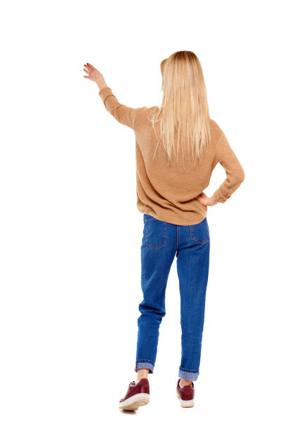 istock Back view of a woman in a sweater points his hand upwards. 1135321470
