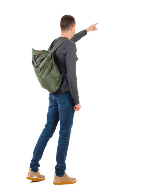 istock Back view of a man with a green backpack pointing forward. 1135323039