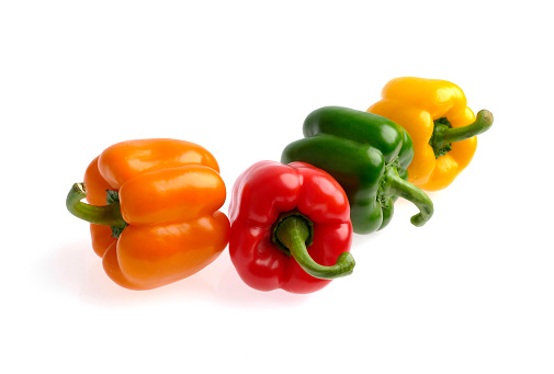 A row of colorful paprika on white