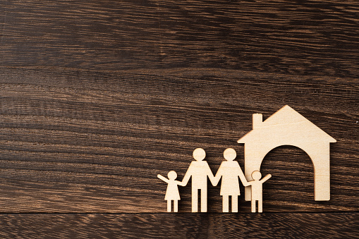 family and design concept - wooden family piece on dark wood background. it's love, protect and secure concept
