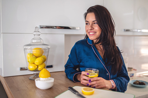 Lovely serene woman drinking lemon water in the morning.