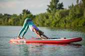 Young woman are doing yoga on a stand up paddle board SUP on a beautiful lake or river