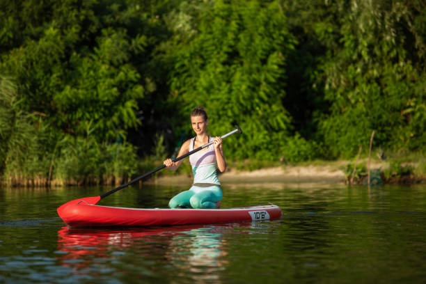 mujer atlética joven haciendo fitness en un tablero con un remo en un lago. - paddleboard oar women lake fotografías e imágenes de stock