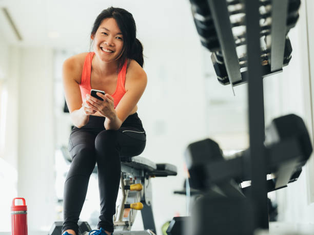 istock Young Asian woman using phone in gym 1135335762