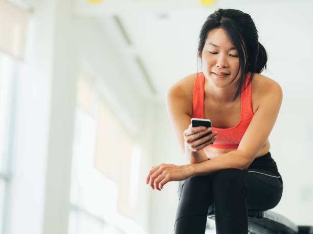 istock Young Asian woman using phone in gym 1135335768
