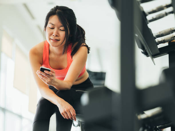 istock Young Asian woman using phone in gym 1135336104