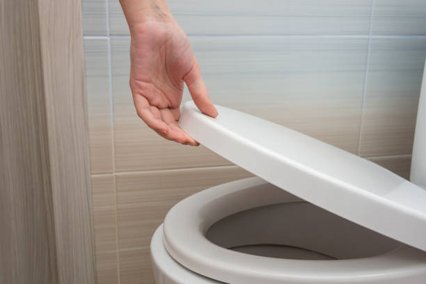 The hand closes or opens the toilet lid The hand closes or opens the toilet lid toilet photos stock pictures, royalty-free photos & images