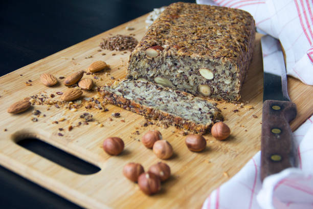 Fresh homemade keto bread with almonds, hazelnuts, sunflower seeds, chia seeds Fresh homemade keto bread with almonds, hazelnuts, sunflower seeds, chia seeds on a wooden cutting board paleo diet photos stock pictures, royalty-free photos & images