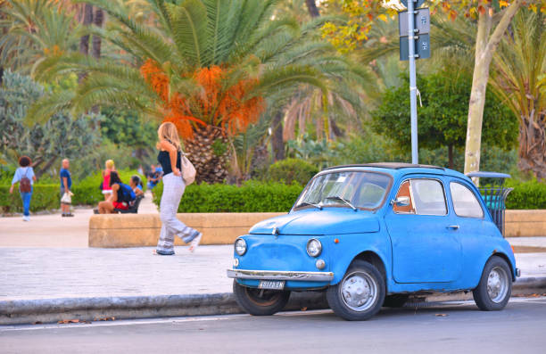 palermo, sicilia italia-coche azul vintage fiat 500 en la calle frente al parque de la ciudad y personas relajantes en palermo en el sur de italia - sicily fiat old car fotografías e imágenes de stock