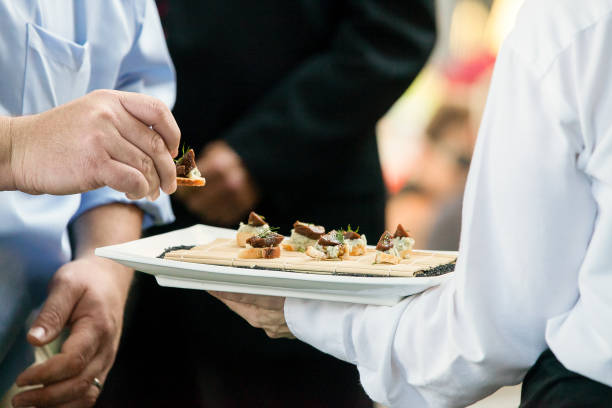 a server holding a tray full of snacks during a catered event a server holding a tray full of snacks during a catered event caterer photos stock pictures, royalty-free photos & images
