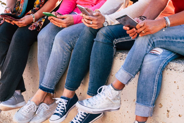 istock Group of modern casual woman unrecognizable sitting on the wall using modern phone devices for social networks and internet media - friendship in modern millennial way - together addicted with technology 1135341835