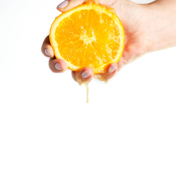 istock female hand crushes orange on white background 1135343877