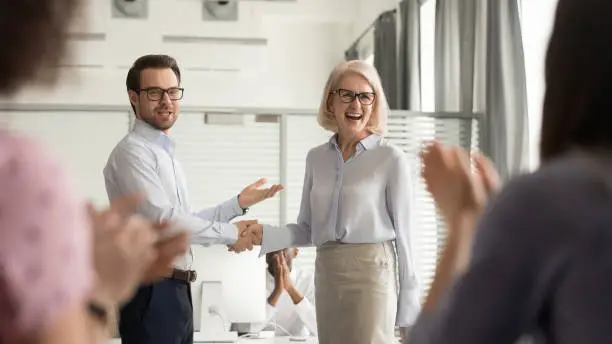 Photo of Happy manager boss praising old employee get team appreciation